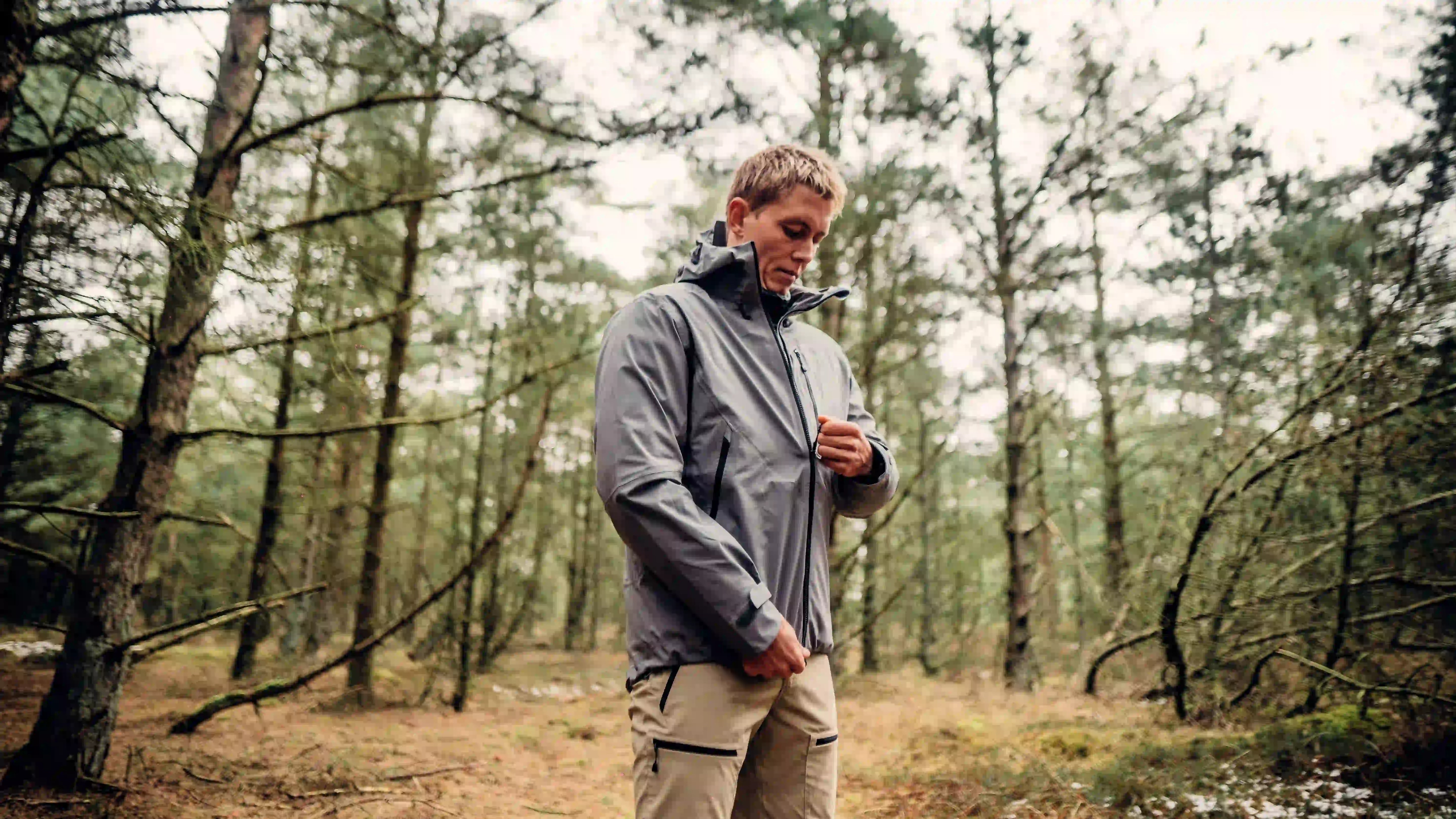 Mand lyner skaljakke op i en skov på fanø